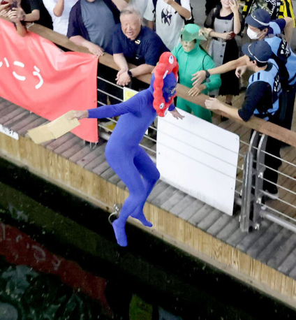 "Shocking: Hanshin Tigers Fan Jumps into Dotonbori River as Osaka Expo Mascot 'Myakumyaku'" — 阪神ファン, 道頓堀川, 大阪イベント